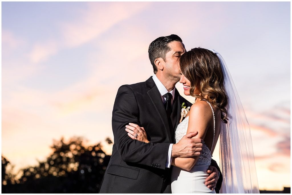 Sunset wedding portrait with groom kissing brides forehead in Philadelphia wedding