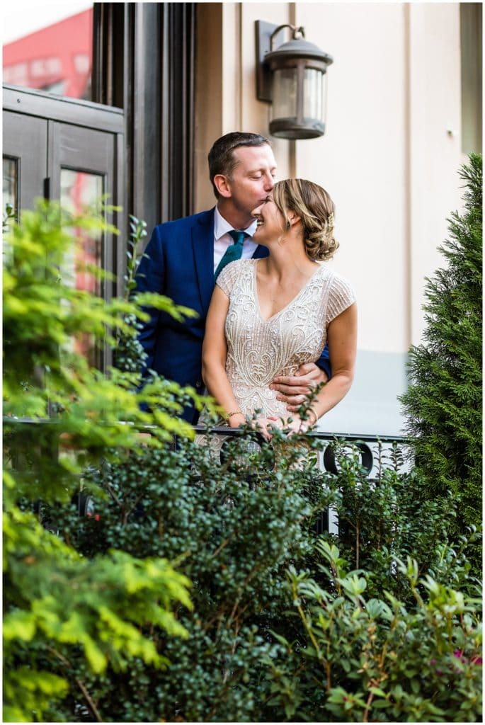 Traditional wedding portrait with groom kissing bride on the forehead on balcony in Philadelphia