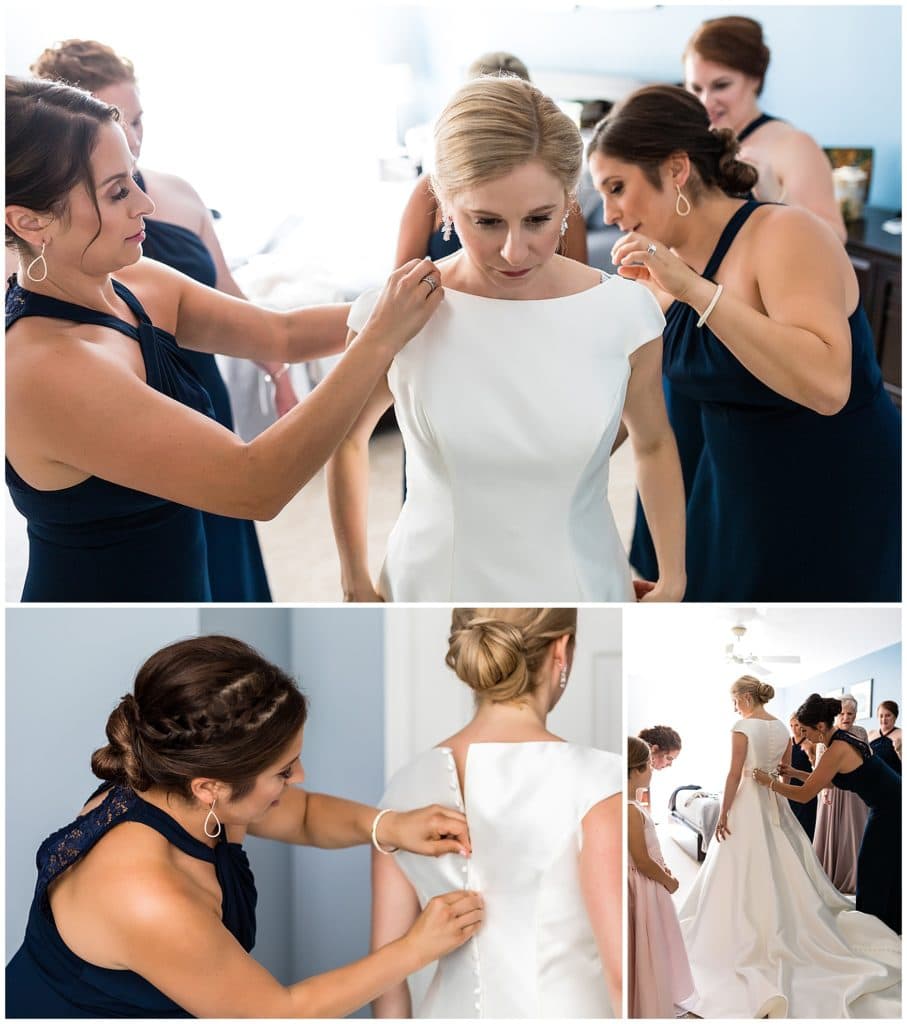 Bridesmaids buttoning brides gown and helping her into her dress