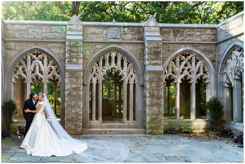 Groom kisses bride on the cheek in outdoor courtyard at Valley Forge National Park