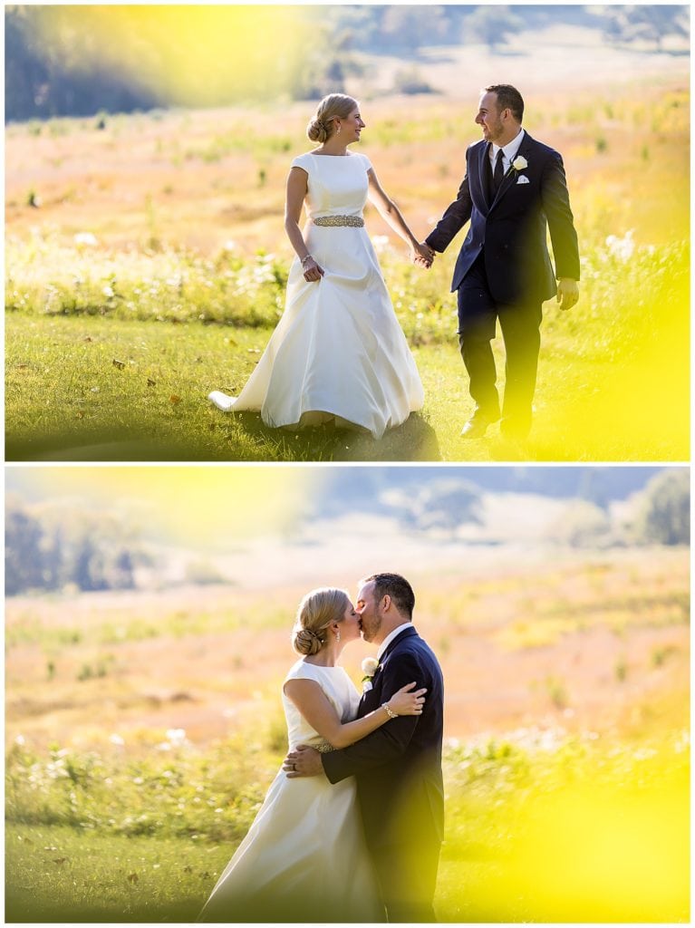 Bride and groom walking through field and kissing in Valley Forge National Park