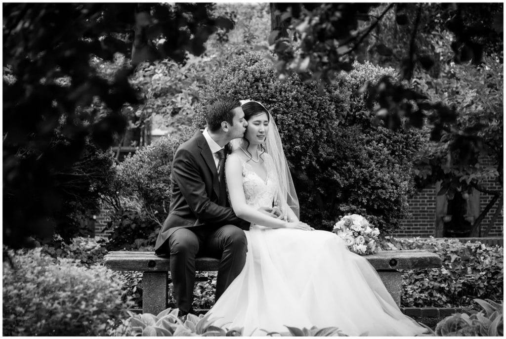 Traditional black and white wedding portrait with groom kissing bride on the cheek