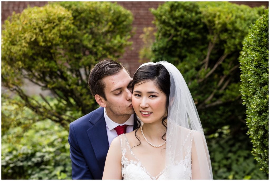 Traditional wedding portrait with groom kissing bride on the cheek