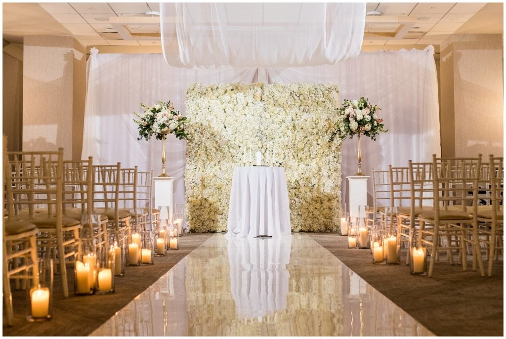 beautiful ceremony in front of floral wall at the Lucy by Cescaphe - Best Philadelphia Wedding Venues