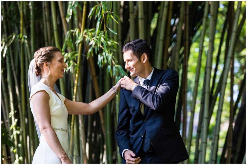 Groom turning around and seeing bride for first time during first look behind tall bamboo 