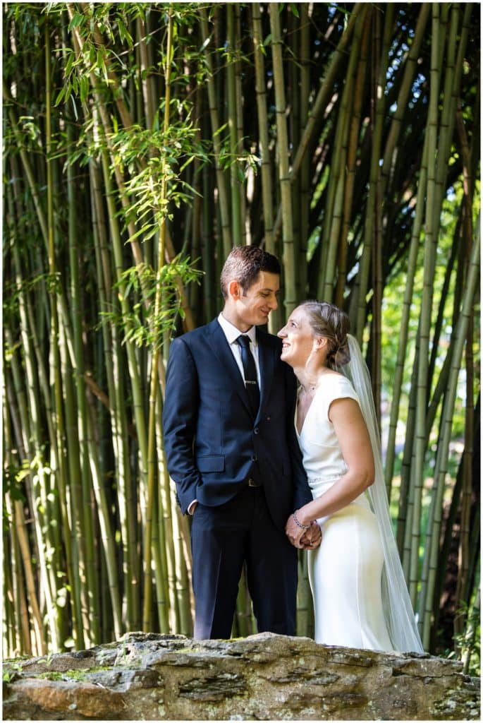 Bride and groom happily smiling at each other portrait in front of bamboo on stone bridge