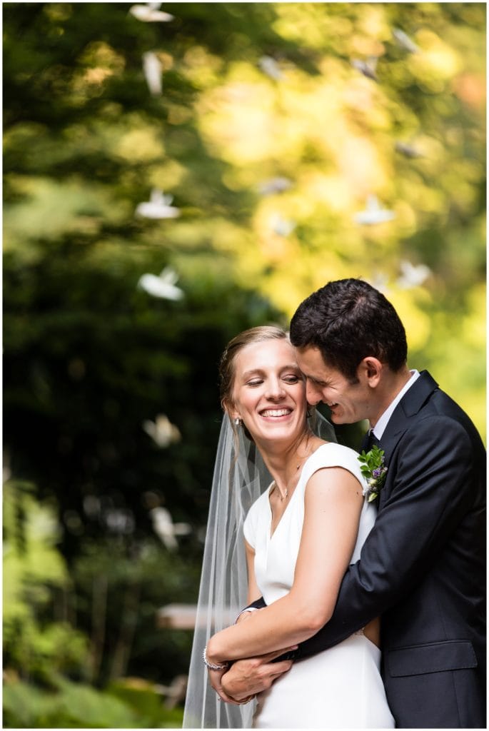 Groom hugs and snuggles bride from behind traditional wedding portrait