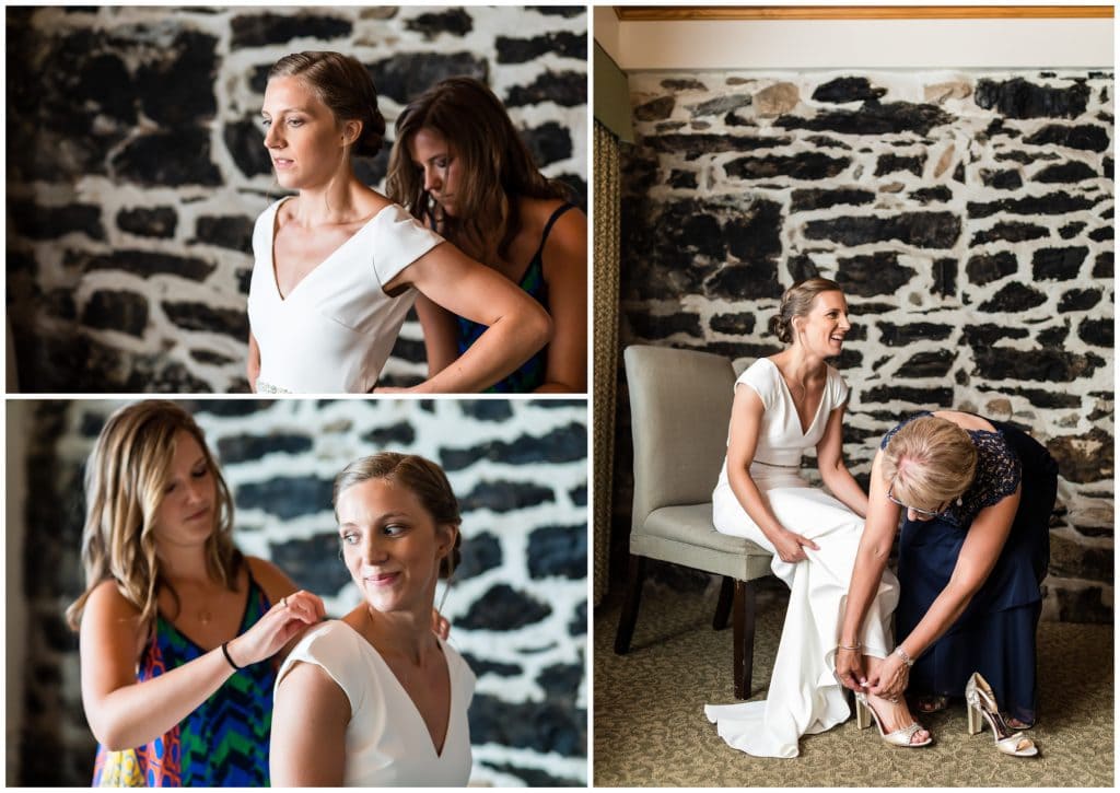 Bridesmaids and mother of the bride helping bride into her wedding gown and shoes