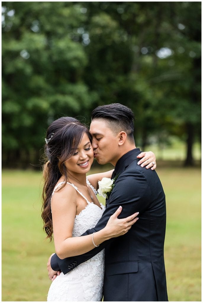 Groom lovingly kisses bride on the cheek wedding portrait