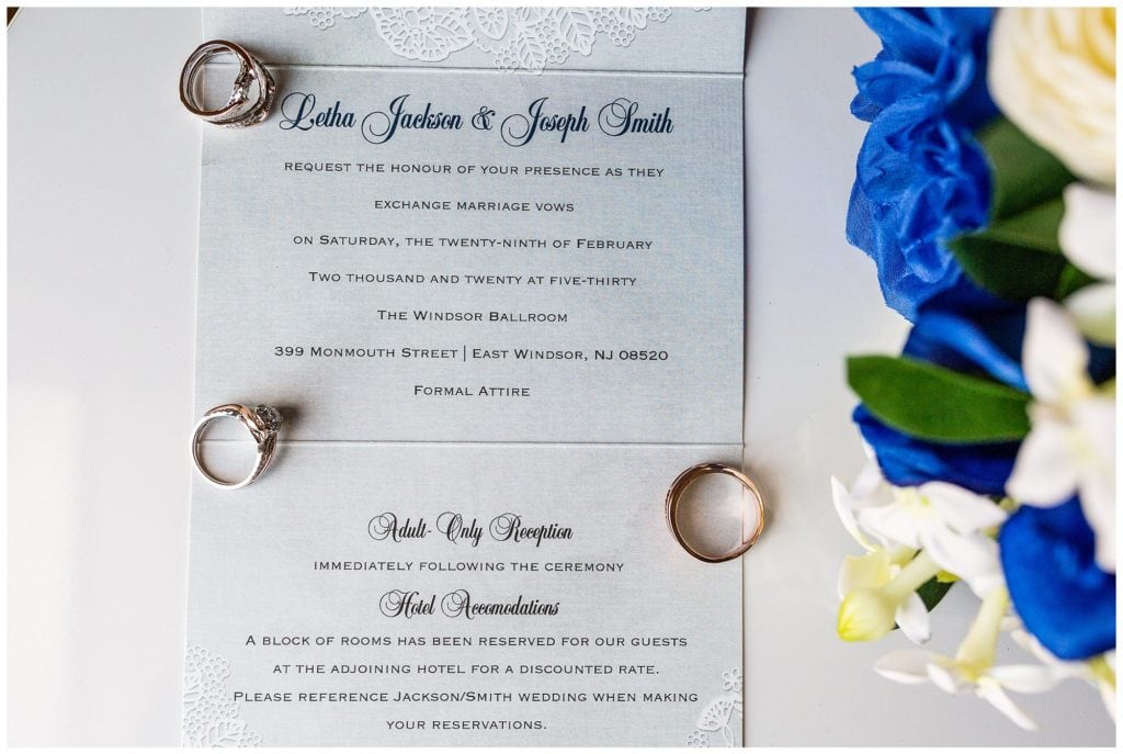 blue and lace invitation suite with wedding rings laid on top