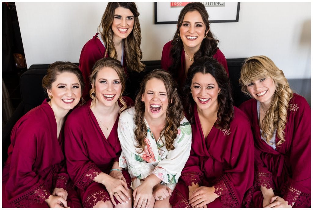 Bridesmaids in matching red robes laughing portrait
