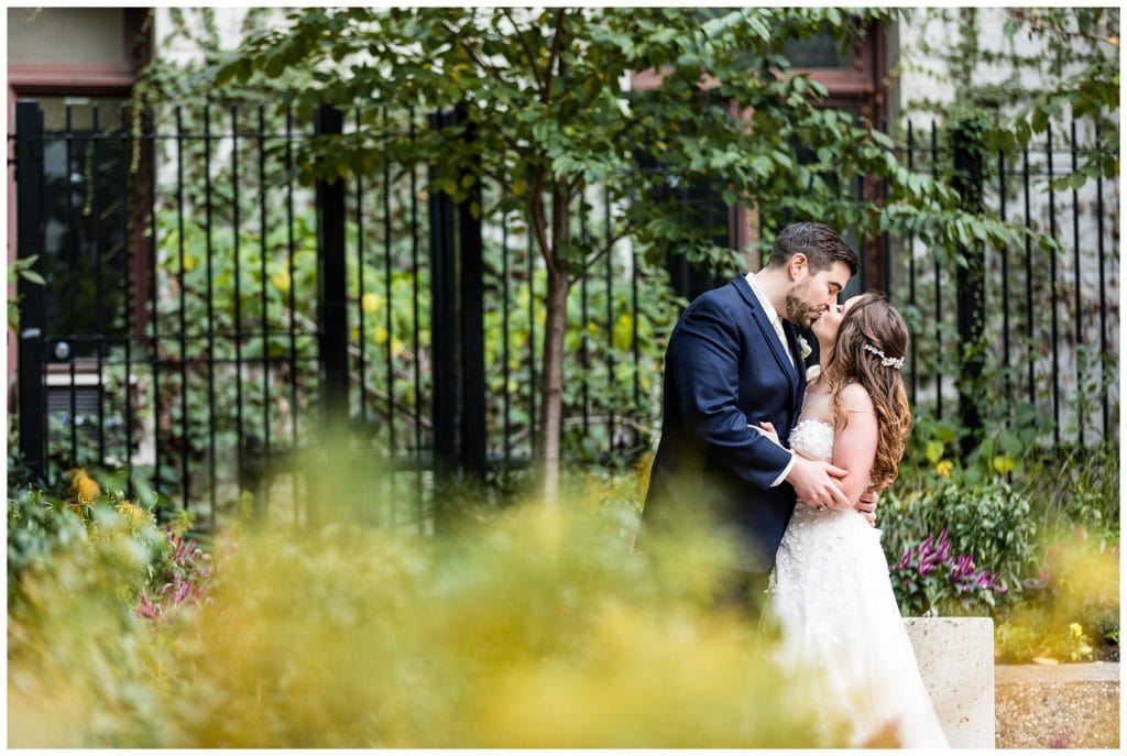 Romantic portrait of bride and groom kissing in gardens at Philadelphia City Hall