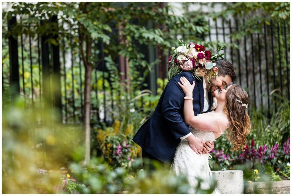 Groom dipping bride for a kiss portrait in Philadelphia City Hall garden