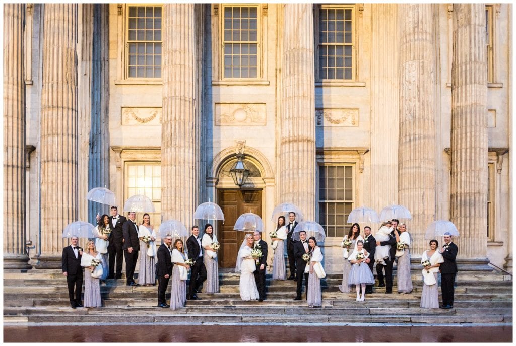 Winter wedding party portrait with umbrellas on steps of First National Bank in Philadelphia