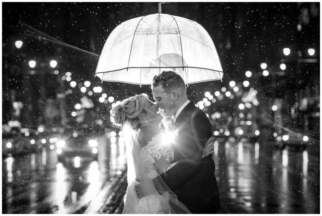 Black and white Bride and groom night rain shot with umbrella on Broad Street Philadelphia