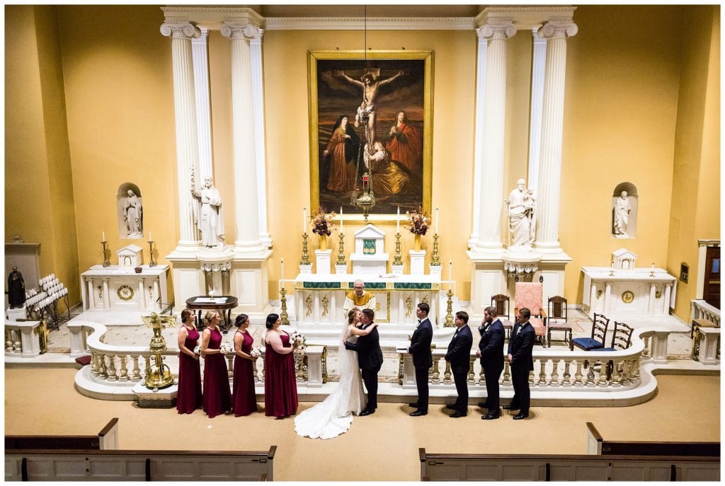 Bride and groom kiss at alter in St Joe's Church wedding ceremony