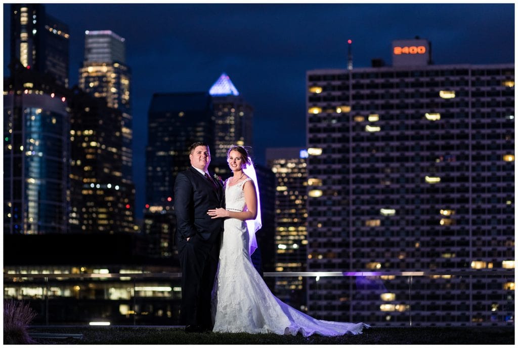 Bride and groom purple lit night portrait with Philadelphia skyline