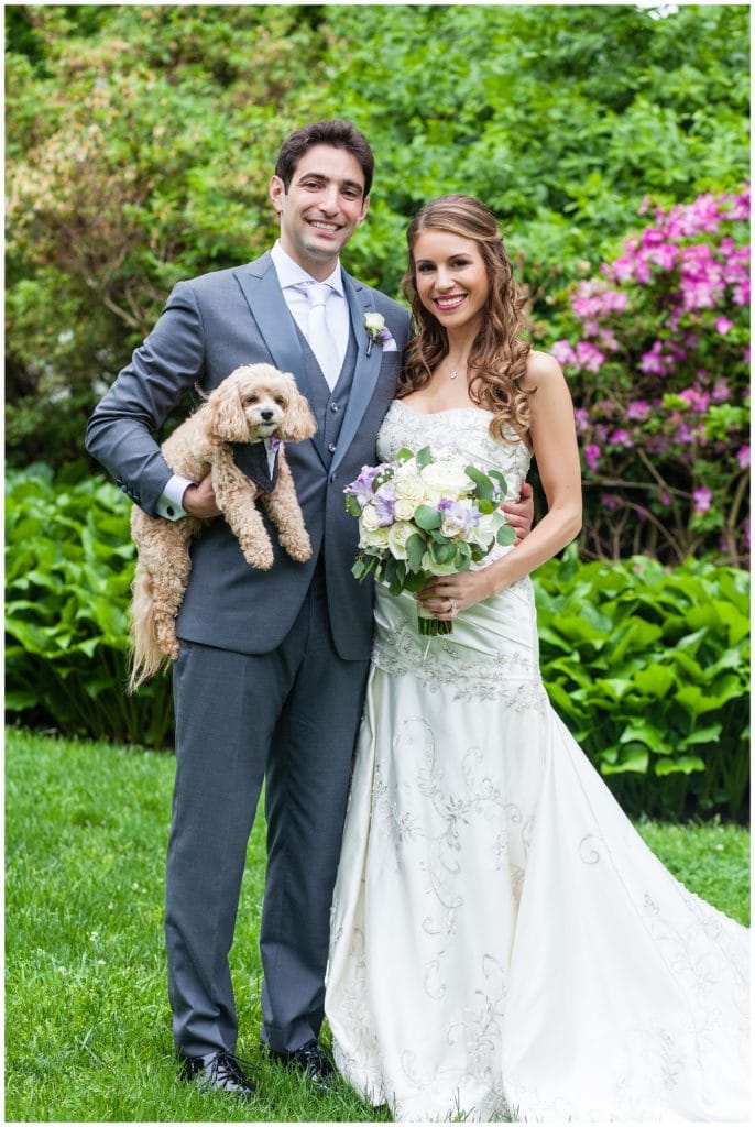 Bride and groom holding puppy portrait in park