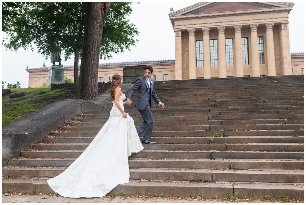 Groom leading bride up stairs in front of Philadelphia Museum of Art