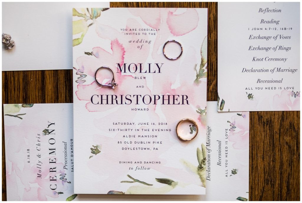 Pink floral wedding invitation suite with engagement ring and wedding bands next to names
