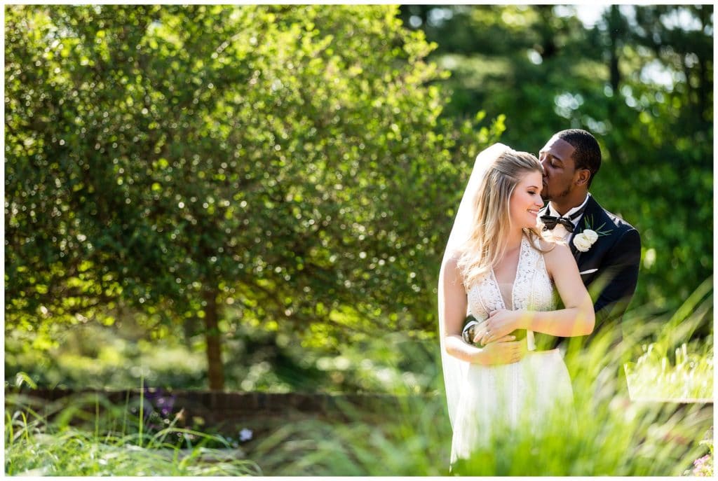 Groom kissing bride on cheek in gardens at Aldie Mansion wedding