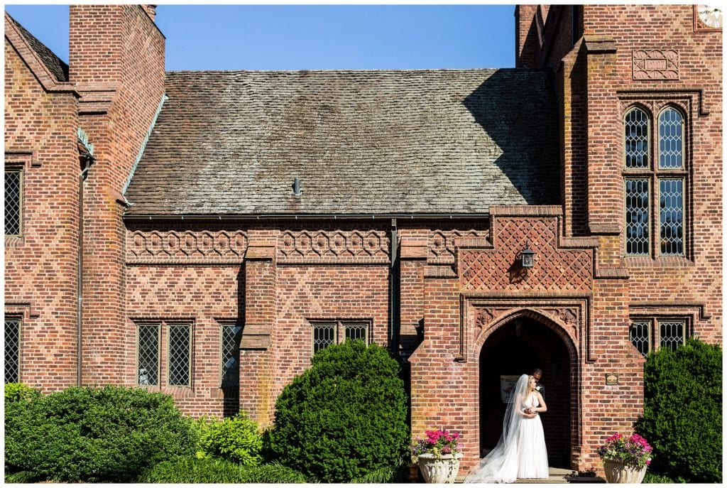Romantic bride and groom wedding portrait with long veil in front of Aldie Mansion