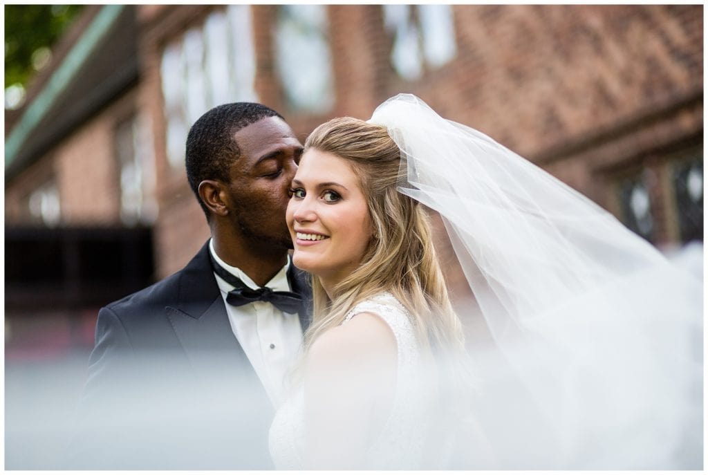 Groom kissing bride on cheek through long veil at Aldie Mansion wedding