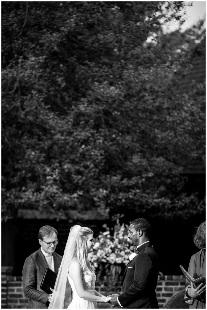 Black and white wedding portrait of bride and groom holding hands at the alter in Aldie Mansion outdoor wedding ceremony