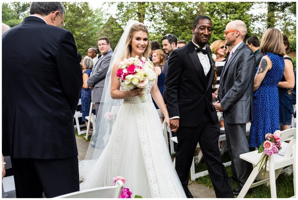 Bride and groom hold hands and walk up aisle at Aldie Mansion outdoor wedding ceremony