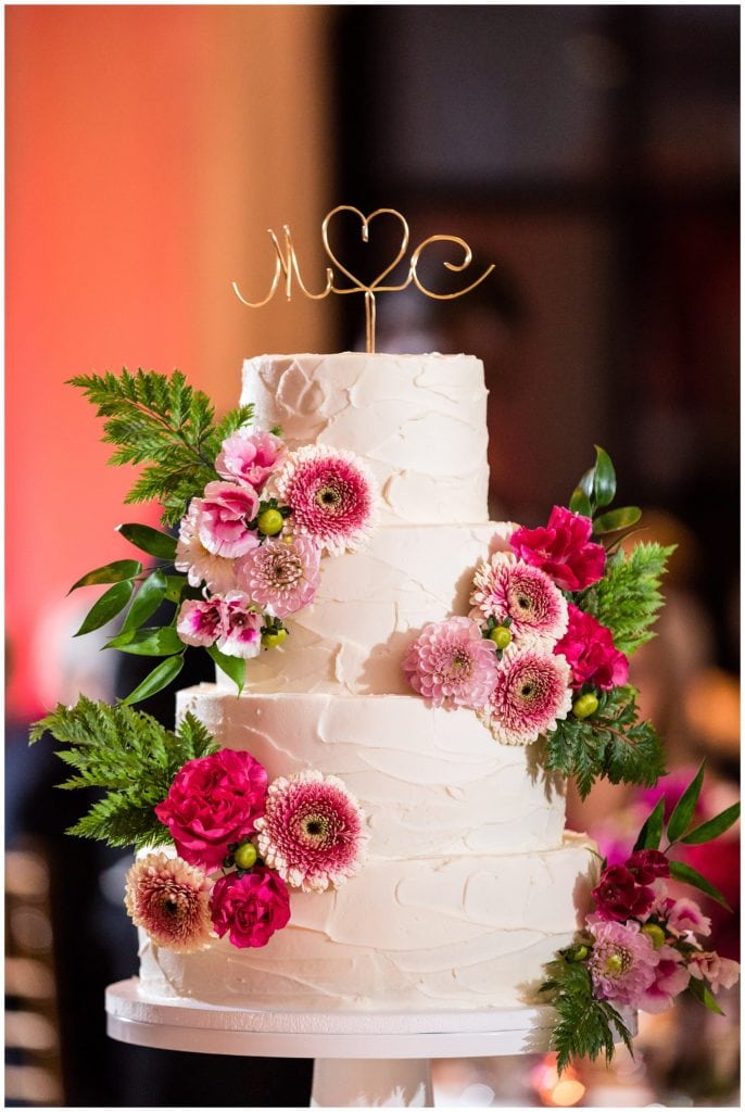 Pink floral wedding cake with greenery and wire initial topper