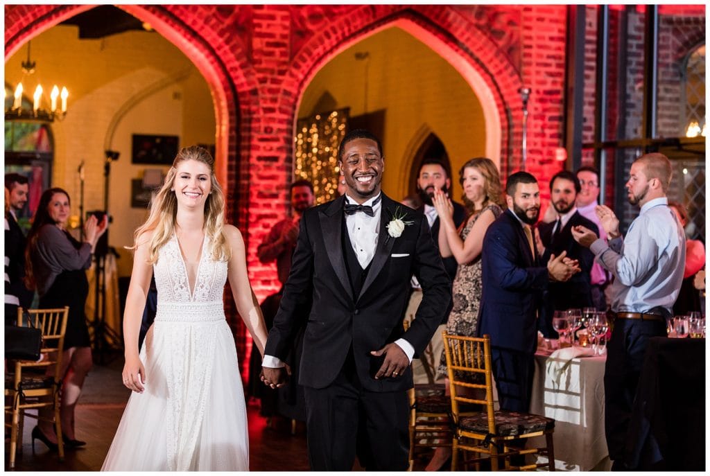 Bride and groom enter wedding reception at Aldie Mansion with red lit walls