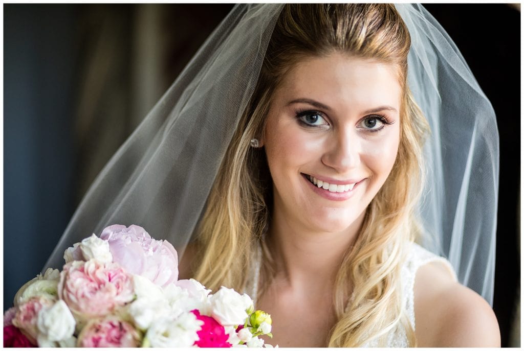 Traditional window lit bridal portrait holding pink and white rose bouquet