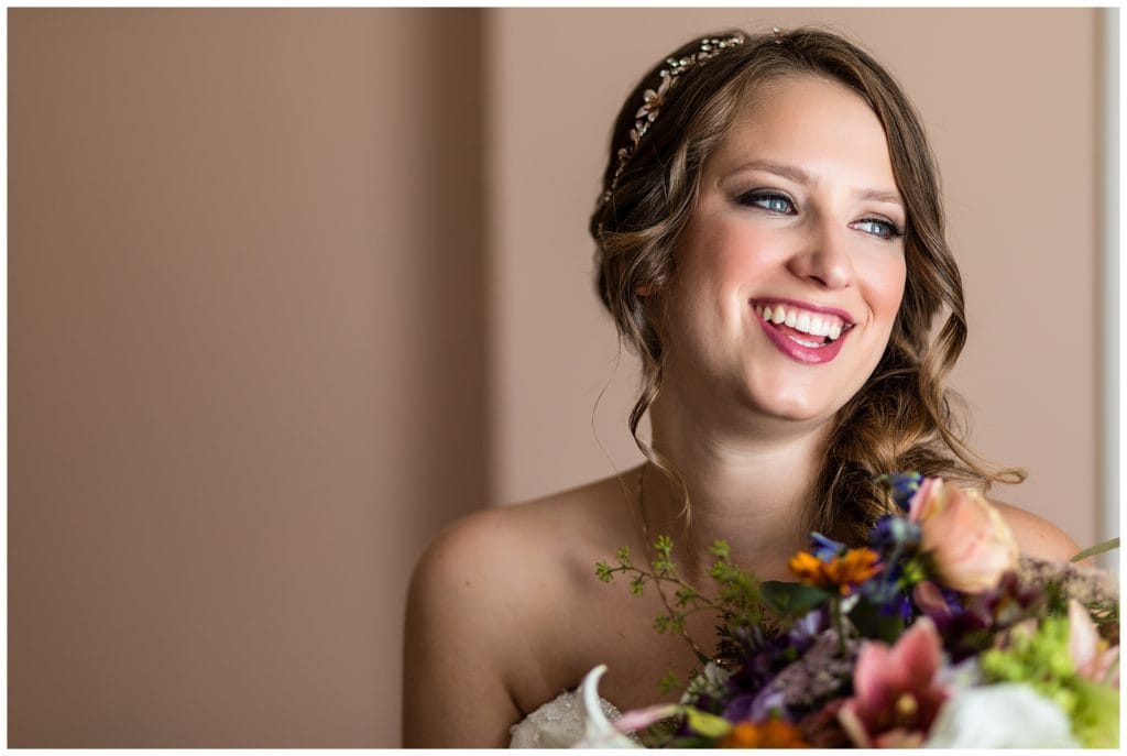 Traditional window-lit bridal portrait with bride laughing