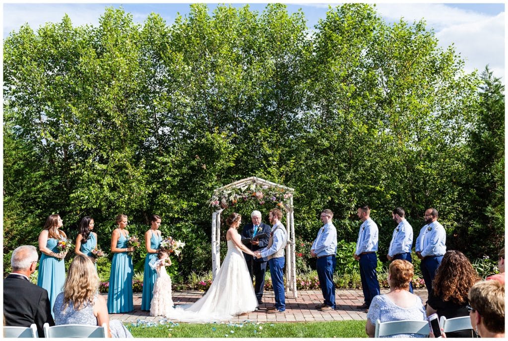 Bride and groom hold hands at alter in outdoor Barn on Bridge wedding ceremony