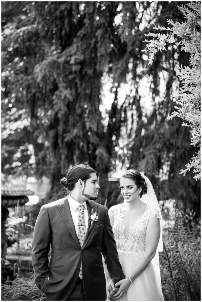 Traditional black and white wedding portrait with groom looking at bride in gardens