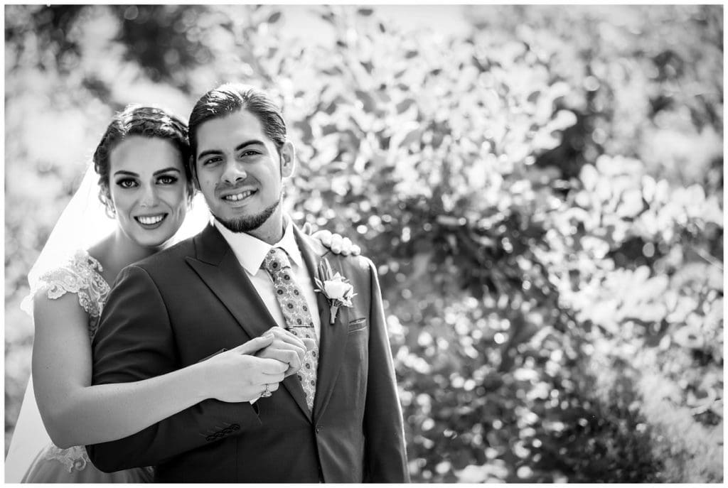 Traditional black and white wedding portrait with bride hugging groom from behind