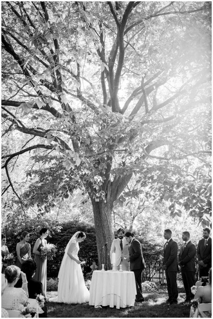 Black and white portrait of bride and groom lighting candles in outdoor wedding ceremony at FEAST at Roundhill