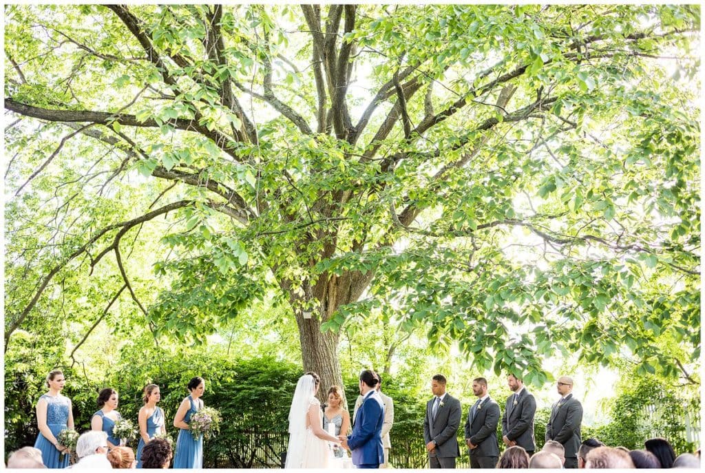 Bride and groom holding hands during outdoor wedding ceremony at FEAST at Roundhill