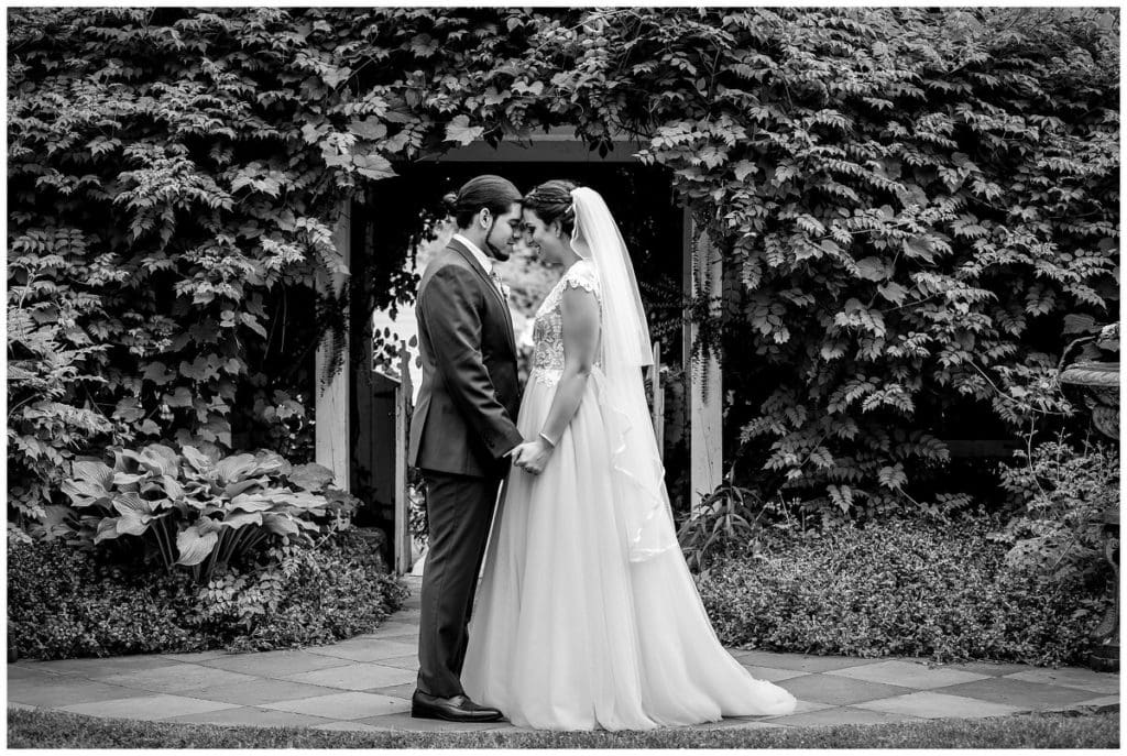 Traditional black and white wedding portrait with bride and groom touching foreheads in gardens at FEAST at Roundhill wedding
