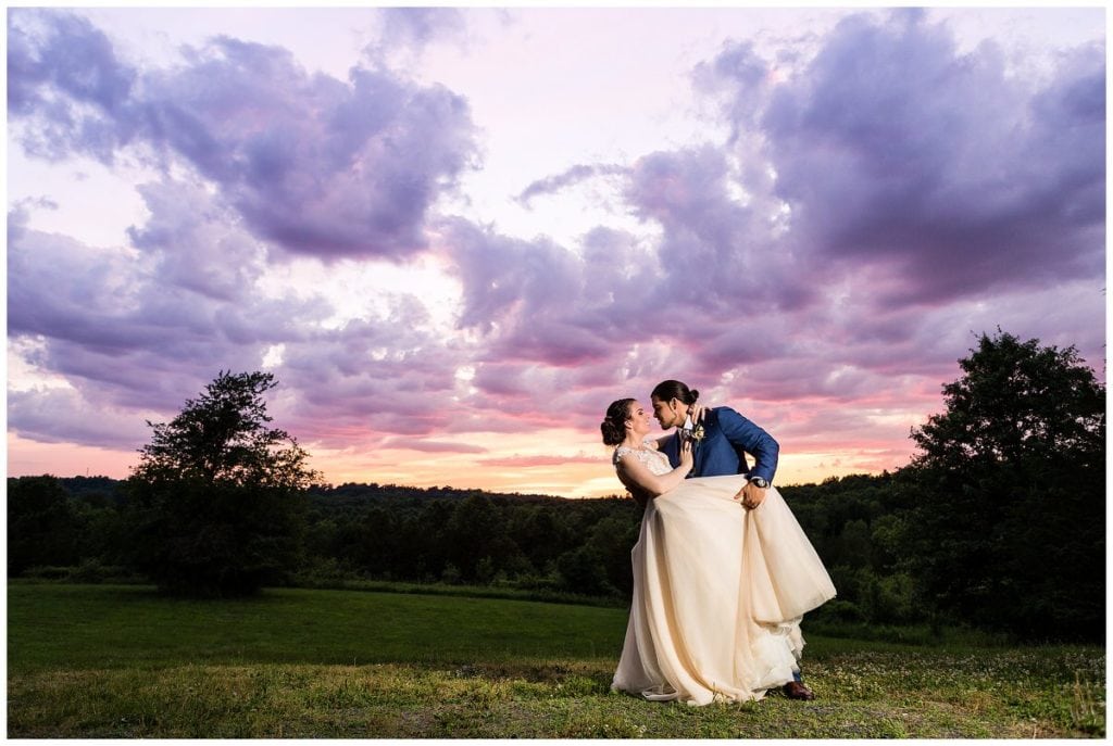 Groom dips bride under purple and pink sunset at FEAST at Roundhill wedding