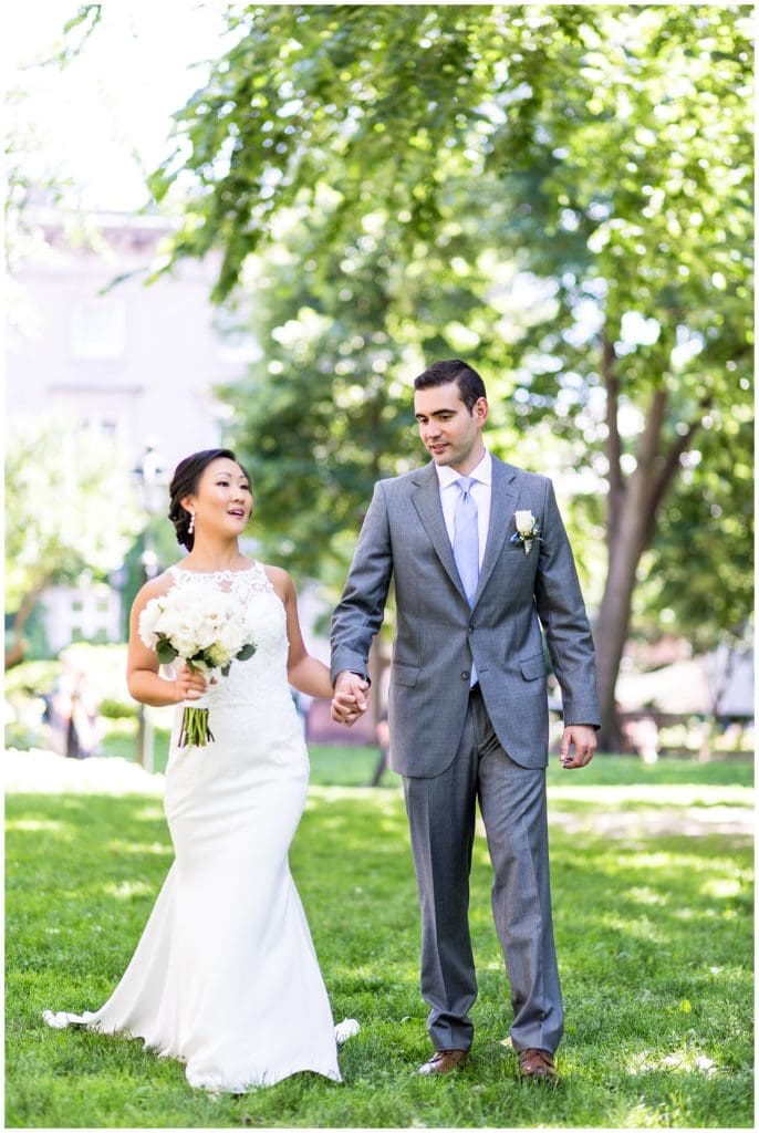 Bride and groom walk holding hands through Philadelphia park