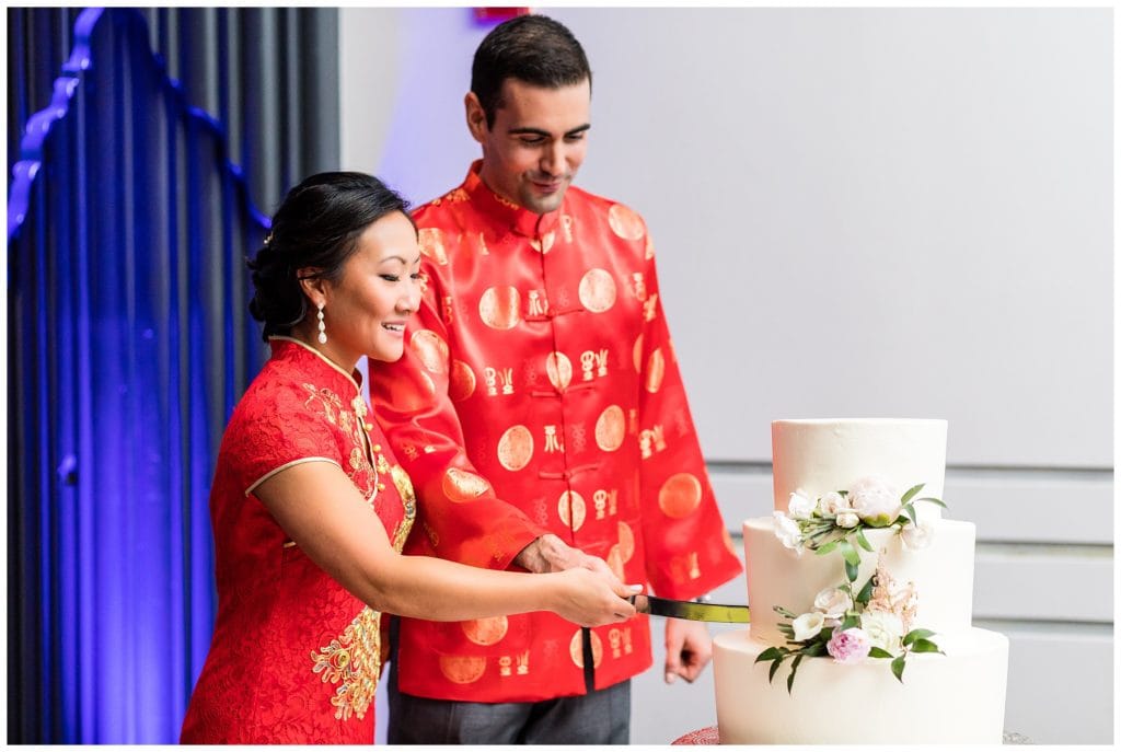 Bride and groom in Asain wedding garments cut wedding cake at Loews Philadelphia wedding reception