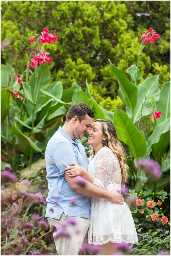 Couple embracing and laughing through flowers at Longwood Gardens engagement portrait session