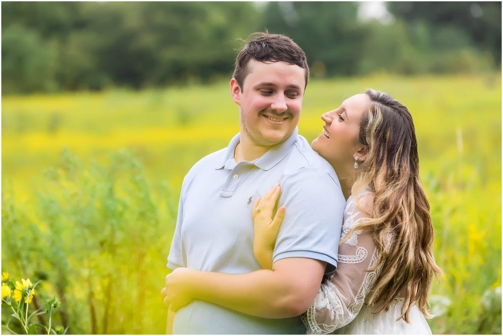Couple embracing and laughing in field of greens at Longwood Gardens engagement session
