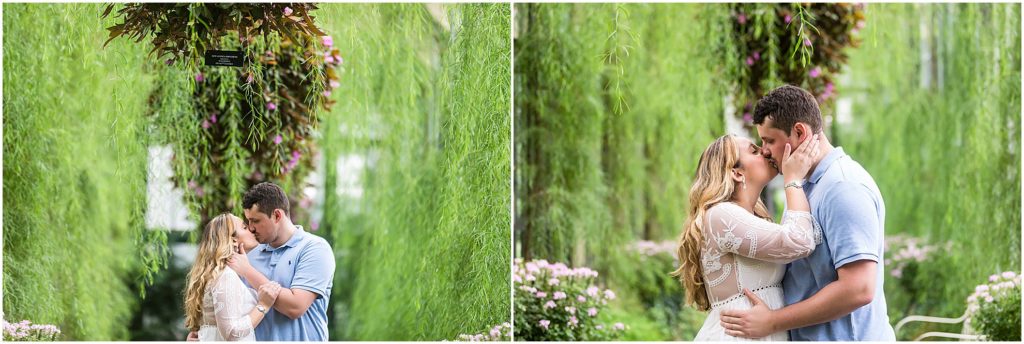 Couple kissing under greenery walkway in Longwood Gardens greenhouse engagement session