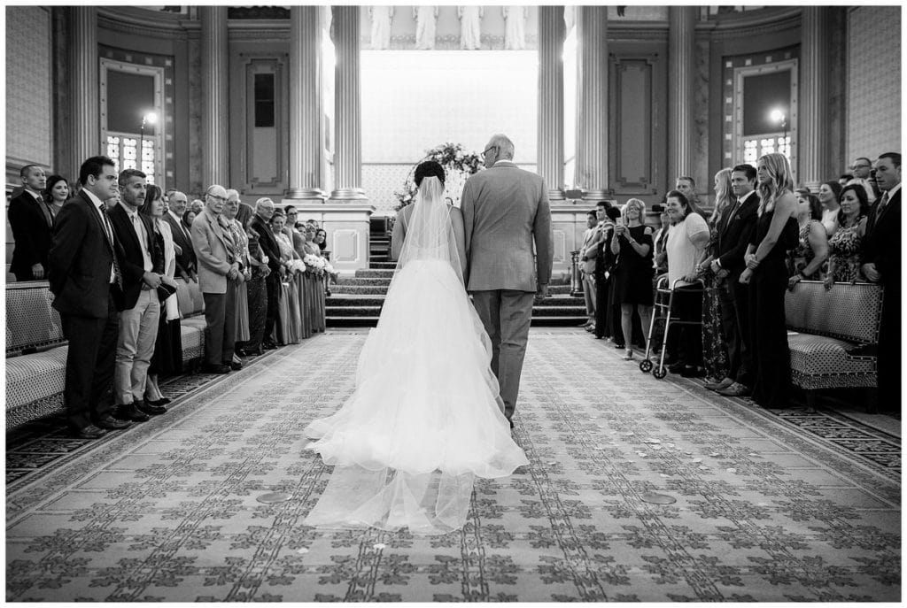 black and white portrait of bride and her father walking down aisle at One North Broad wedding ceremony