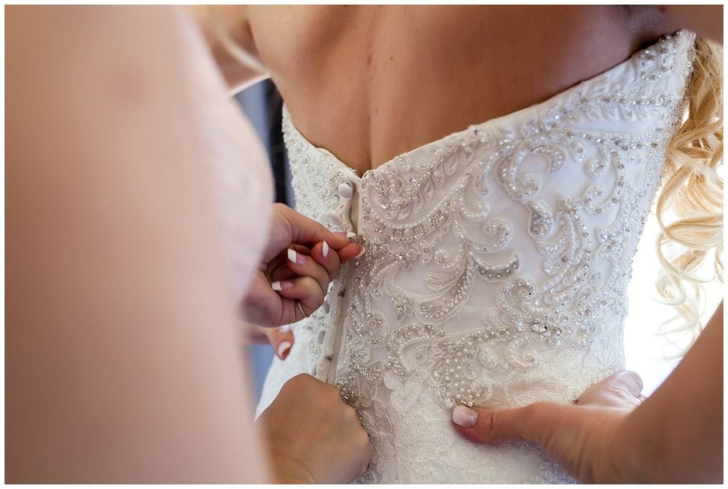 Buttoning and zipping lace beaded bridal gown close up
