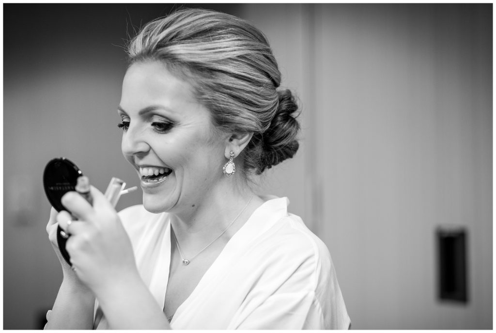 Black and white bridal portrait of bride putting on lipgloss