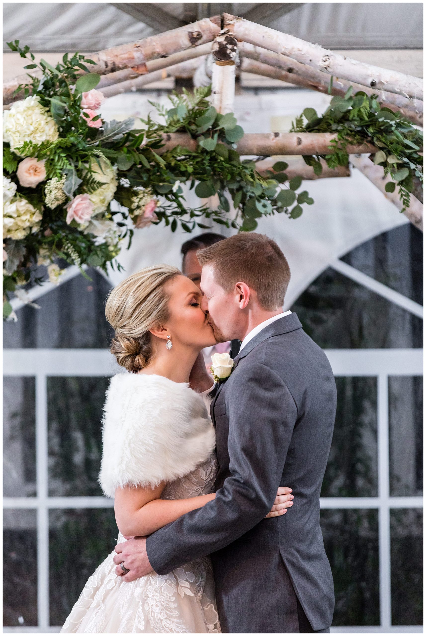 Bride and groom kiss at outdoor winter wedding ceremony at Barn on Bridge