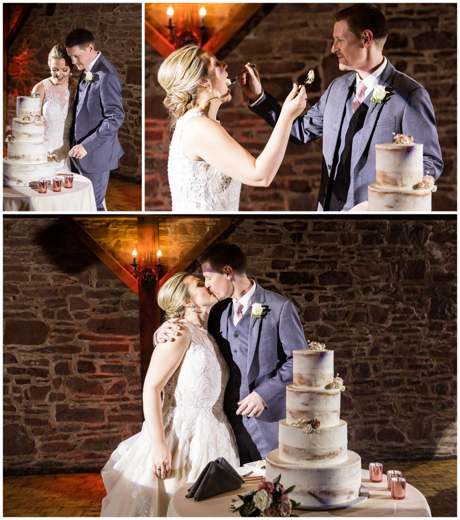 Bride and groom cut cake, feed a piece of cake to each other, and kiss at barn on Bridge winter holiday wedding reception